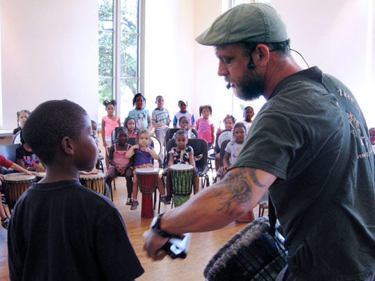 Boy assisting presenter at drum circle program